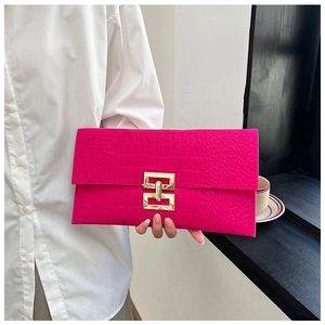 Détail de la pochette fuchsia à motif crocodile avec fermoir géométrique en métal doré