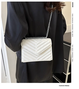 Close-up of white V-quilted crossbody bag with elegant silver chain shoulder strap detail