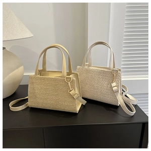 Detail of minimalist straw tote bags with woven texture and gold metal buckle hardware