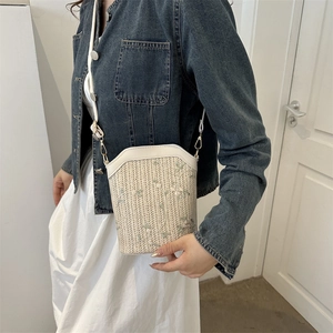 Straw crossbody bag with floral embroidery and white leather strap on a model
