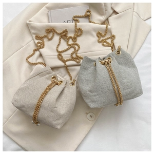 Gros plan sur les mini sacs seaux tissés avec chaînes dorées et détails de perles
