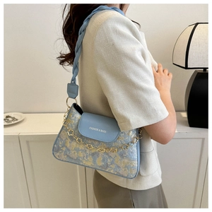Détail du sac bandoulière bleu clair avec broderie et chaîne fleurie dorée