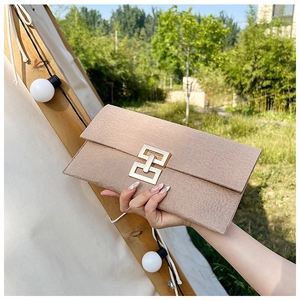 Détail d'une pochette en texture crocodile kaki clair avec fermoir en métal doré