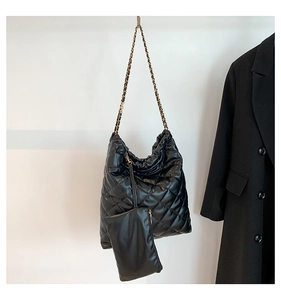 Détail d'un cabas noir matelassé avec bandoulière en chaîne et petit porte-monnaie