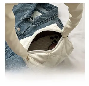 Close-up of a white quilted shoulder bag showing interior space for phone and sunglasses