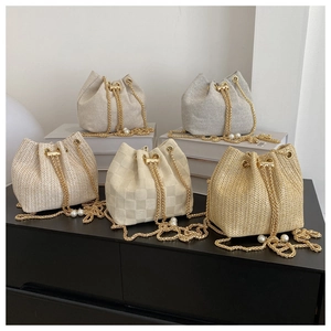 Detail of woven bucket bags with elegant pearl drawstring and gold metal chain straps
