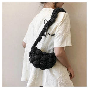 Detail of black quilted bubble texture on crescent shoulder bag with pleated strap