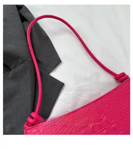 Détail du sac à main rose en relief crocodile avec design de nœud sur la bandoulière