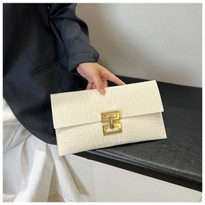 Détail d'une pochette blanche motif crocodile avec rabat enveloppe et fermoir doré