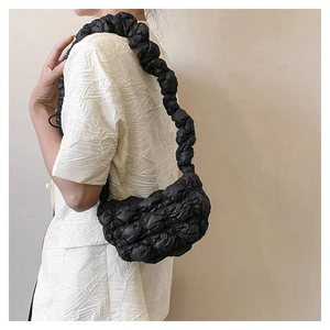 Detail of black quilted cloud bag with scrunchie strap worn over the shoulder
