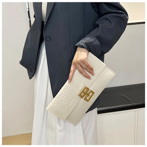 Gros plan sur un sac à main blanc à motif crocodile et fermoir en métal doré