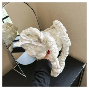Detail of white quilted cloud bag featuring puff texture and decorative bow accent