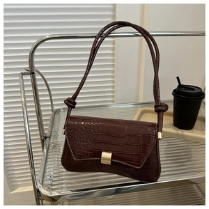 Detail der dunkelbraunen Kroko-Handtasche mit goldener Schnalle und Knotengurt