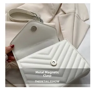 Close-up of chevron quilted white leather bag with magnetic buckle and silver chain strap