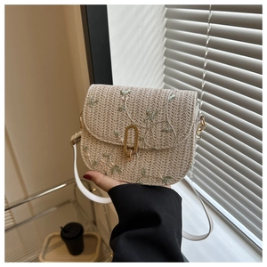 Detail of woven straw handbag with floral embroidery and gold metal clasp closure