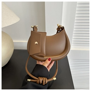 Detailansicht der braunen Leder-Halbmondtasche mit Goldbeschlägen und kleinem Beutel