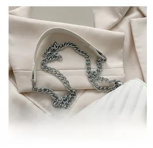 Close-up of white quilted crossbody bag with V-shaped stitching and silver metal chain strap