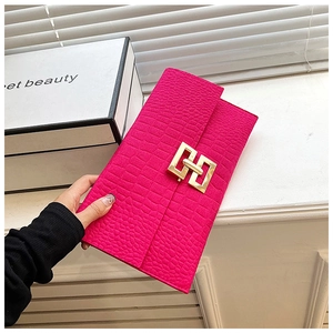 Détail d'une pochette enveloppe rose rouge avec texture croco et fermoir doré