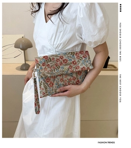 Detail of floral tapestry clutch bag with golden flower clasp and wrist strap