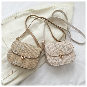 Detailed view of woven straw shoulder bags with floral embroidery and gold metal clasps