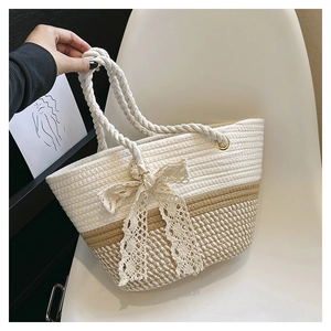 Détail d'un sac cabas tissé avec nœud en dentelle blanche et poignée en corde sur chaise