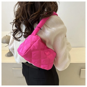 Detailed back view of a magenta quilted puffer bag with crossbody strap on a model