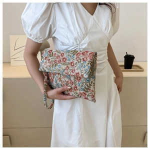 Detail of floral envelope clutch bag with metal flower buckle and matching wrist strap