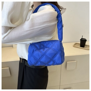 Detail of Klein blue quilted puffer bag with crossbody strap on a model's shoulder