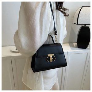 Dettaglio della borsa in pelle nera con l'esclusiva chiusura in metallo a forma di T oro