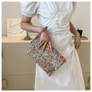 Close-up of floral tapestry envelope clutch with gold clover lock and wristlet strap