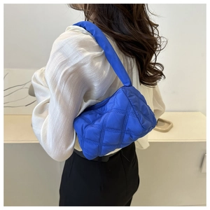 Close-up of bright blue quilted shoulder bag showing diamond stitching and puffy texture