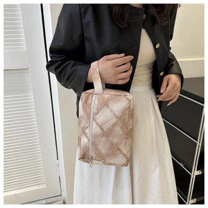 Detail der braunen gesteppten Kosmetiktasche mit Reißverschluss, von Model getragen