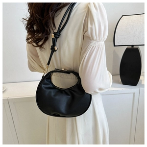 Détail d'un sac demi-lune noir avec bandoulière à nœud et détails en métal doré