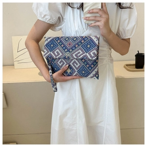 Detailed shot of ethnic geometric woven envelope clutch with floral metal clasp and wristlet