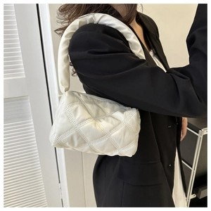 Detailed side view of a white quilted shoulder bag with diamond stitching on a model