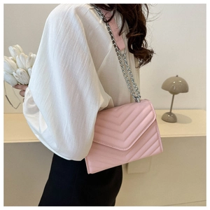 Detailed side view of pink V-quilted faux leather shoulder bag with silver chain strap
