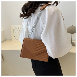 Detail of caramel quilted crossbody bag with chevron pattern and silver chain strap