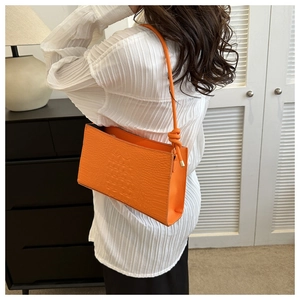 Vue détaillée d'un petit sac carré orange vif à motif crocodile porté à l'épaule