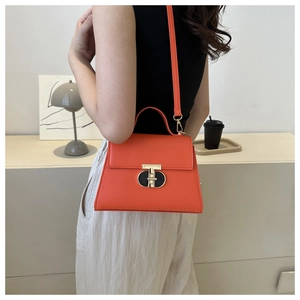 Dettaglio della borsa a tracolla in pelle PU arancione con chiusura a T dorata in stile minimal
