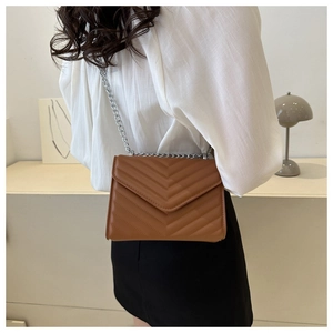 Detail view of brown V-quilted faux leather crossbody bag with silver chain strap