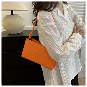 Détail de la texture crocodile orange vif sur un sac sous le bras très élégant