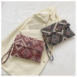Close-up of ethnic envelope clutches featuring geometric embroidery and clover metal clasps