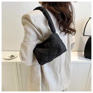 Rear view of a black quilted puffer shoulder bag with a cloud-like texture on a chic model
