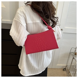Modèle portant un sac sous le bras rose motif crocodile montrant taille et style