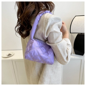 Close-up of a purple quilted puffer bag with rhombic stitching and soft padded strap