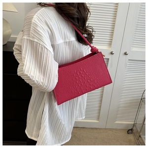 Détail d'un sac porté épaule fuchsia à relief crocodile sur chemise blanche