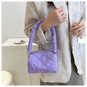 Detail of light purple quilted handbag featuring diamond embroidery and a padded handle