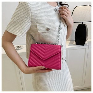 Close-up of fuchsia quilted shoulder bag with V-stitch design and silver chain strap