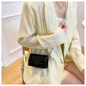 Close-up of black crocodile pattern crossbody bag with silver chain on model