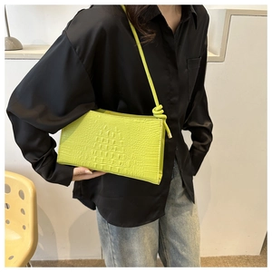 Détail du sac sous le bras vert néon à motif crocodile avec bandoulière à nœud chic